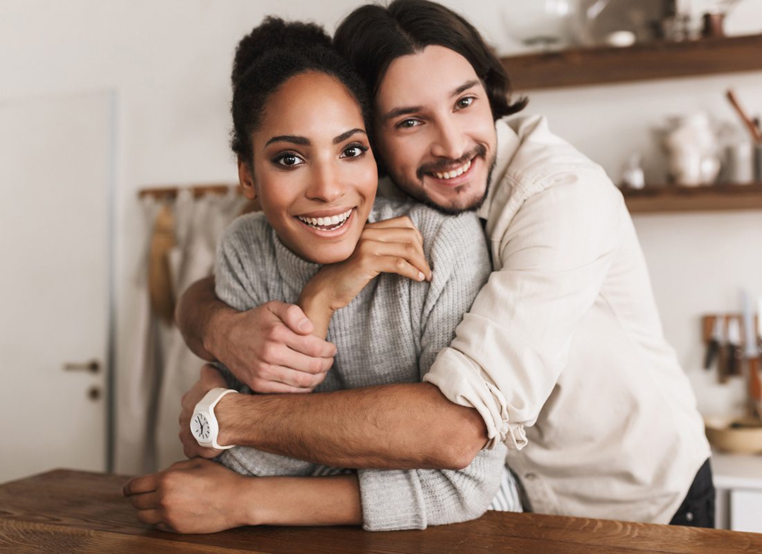 Personal Insurance - Happy Couple Embrace Each Other in the Kitchen of Their Home